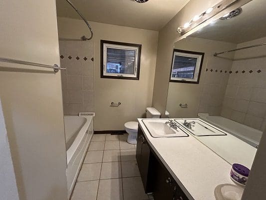 Bathroom with tub, double sinks, and tiled walls.