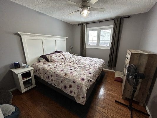 Bedroom with floral bedding and hardwood floor.