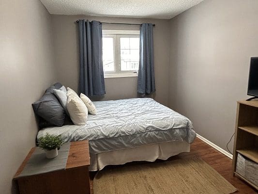 Bedroom with bed, pillows, and curtains.