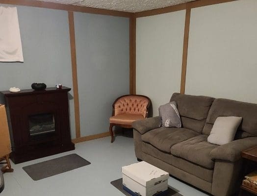 Basement living room with couch and fireplace.