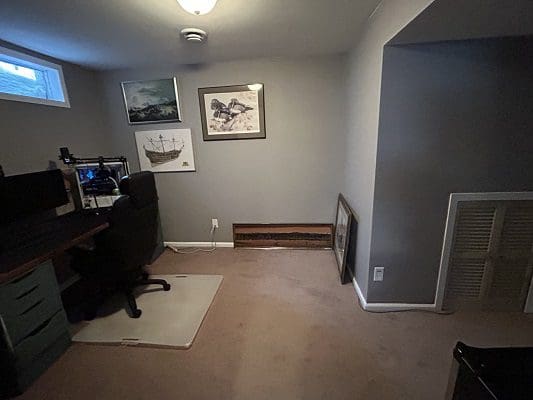 Basement office with computer and artwork.