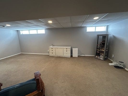 Finished basement with windows and furniture.