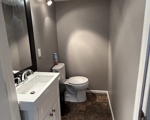 Small gray bathroom with white sink and toilet.