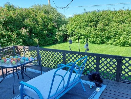 Deck with blue chair and green yard.
