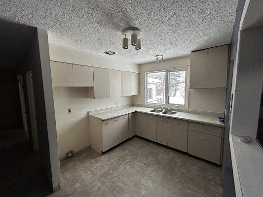 Kitchen with beige cabinets and window.