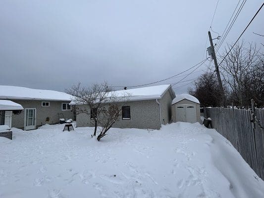 Snow-covered house and shed in winter.