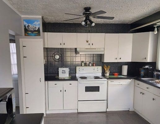 White kitchen with appliances and artwork.
