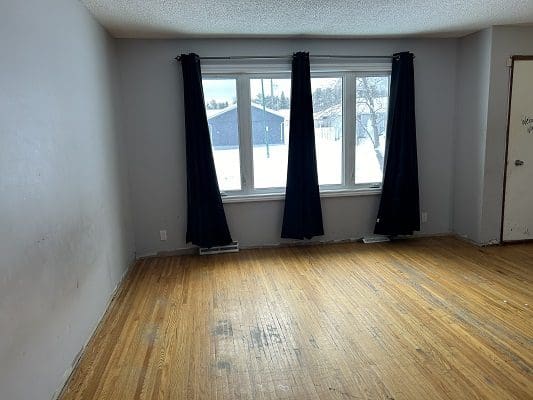 Empty living room with hardwood floors.