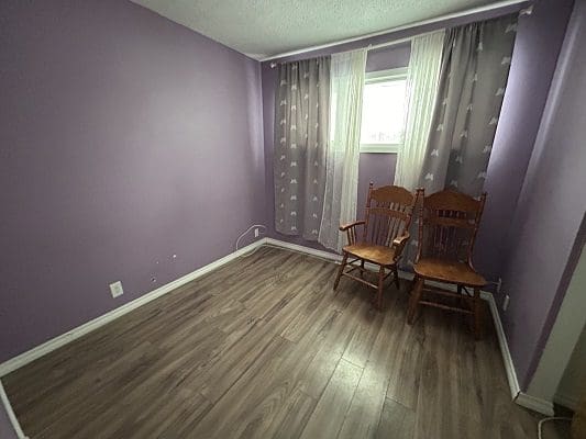 Purple bedroom with two wooden chairs.