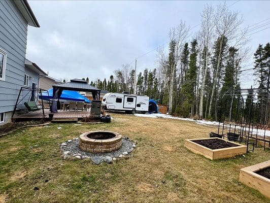 House, camper, fire pit, garden beds.