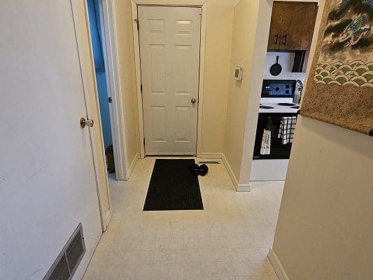 Here's an alt text option for the image: > Entryway with door and kitchen view.