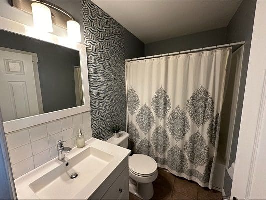 Bathroom with shower and patterned curtain.