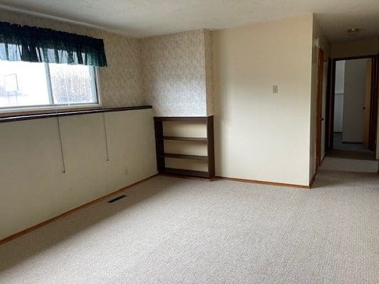 Empty carpeted room with built-in shelves.