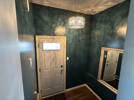 Entryway with teal walls, door, and light fixture.
