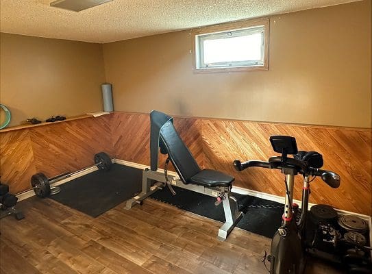 Home gym with weight bench and bike.