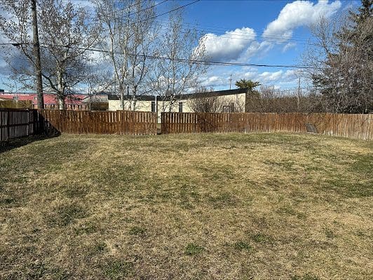 Backyard with wooden fence and grass.
