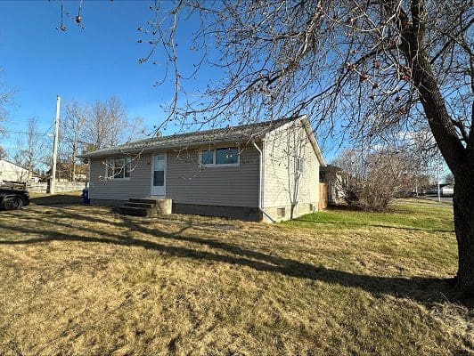 Beige house with yard and tree.