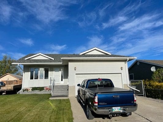 Suburban house with blue truck in driveway.