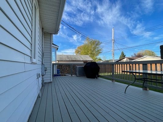 Grey deck with grill and table outdoors.