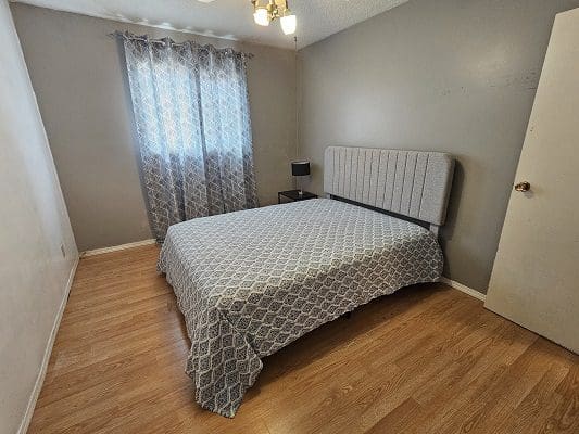 Bedroom with patterned bed and hardwood floor.