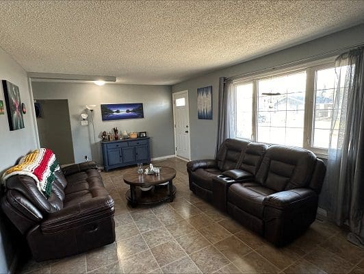 Living room with leather couches and large windows.