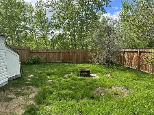 Backyard with fire pit and wooden fence.
