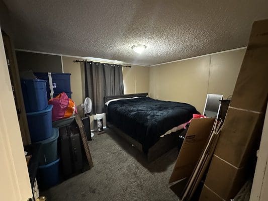 Bedroom with bed and stacked boxes.