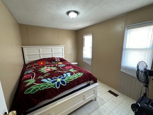 Bedroom with floral bedspread and windows.