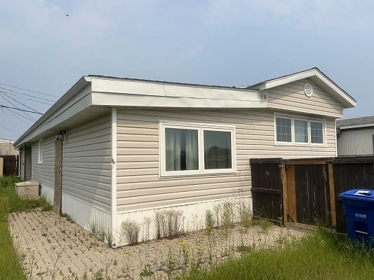 Beige mobile home with windows and fence.