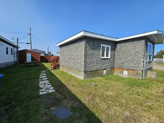 Stone-faced house with yard and shed.