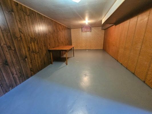 Basement with wood paneling and table.