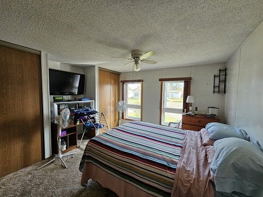Bedroom with striped bed and TV.