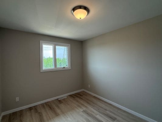 Empty room with window and wooden floor.