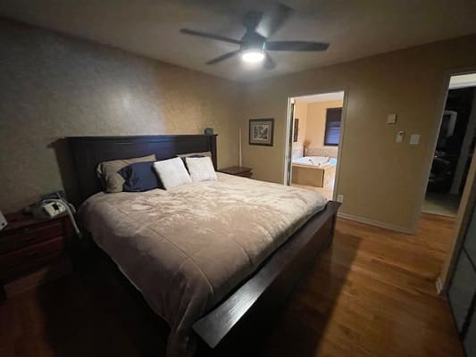 Cozy bedroom with large bed and fan.