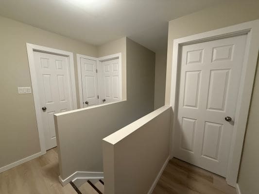 Hallway with three white doors and stairs.