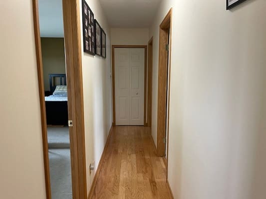 Wooden hallway with bedroom and closed door.