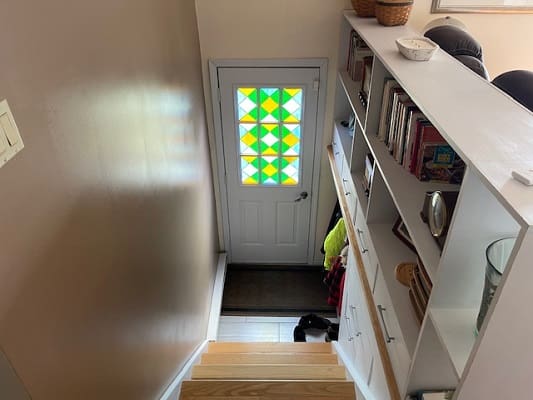 Stairway with patterned door and bookshelves.