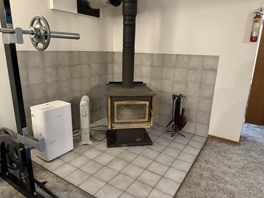 Wood stove in tiled corner with equipment.