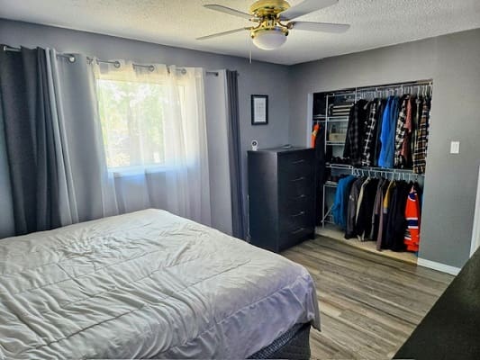 Bedroom with bed, closet, dresser, and window.