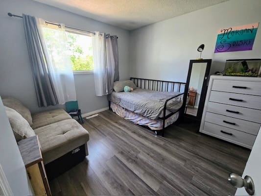 Small bedroom with bed and dresser.