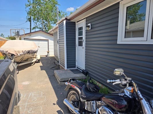 Motorcycle parked beside house and covered boat.