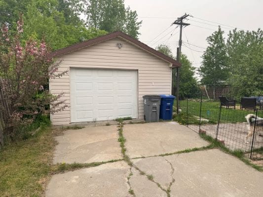 Garage with driveway and trash bins.