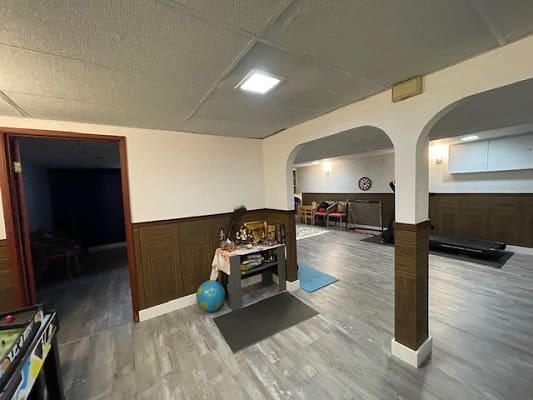 Spacious basement with archways and wood paneling.