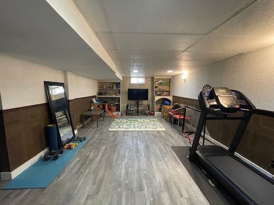 Home gym with treadmill and TV setup.