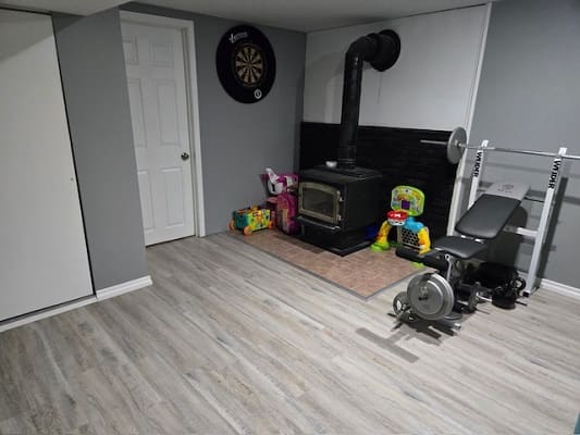 Basement with dartboard, wood stove, exercise equipment.