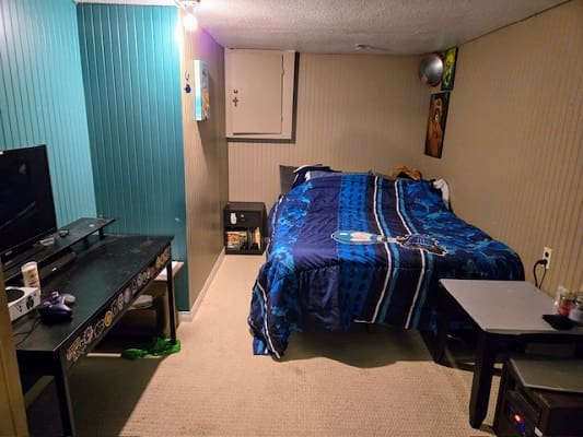 Small bedroom with bed and TV setup.