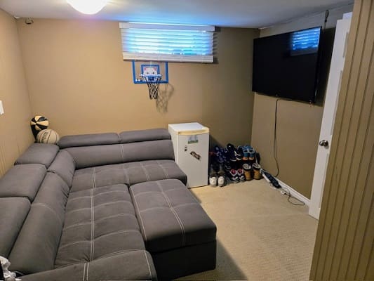 Cozy basement with sofa and mini basketball hoop.