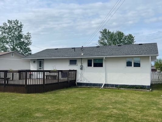 Backyard view of house with wooden deck.