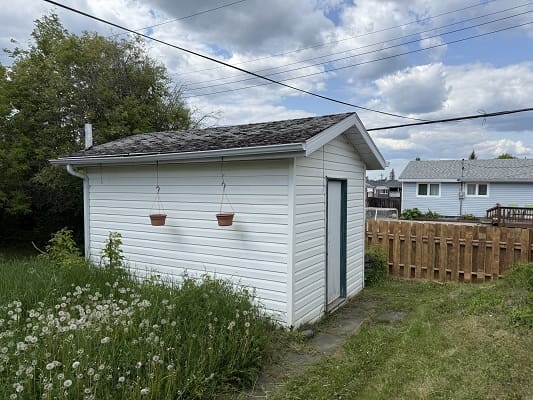 Small white shed with hanging pots.