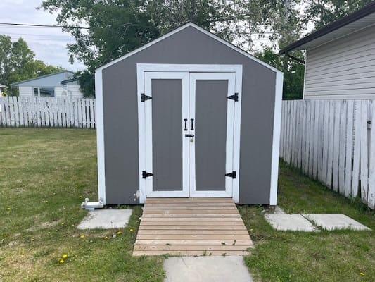 Small grey shed with wooden pathway.